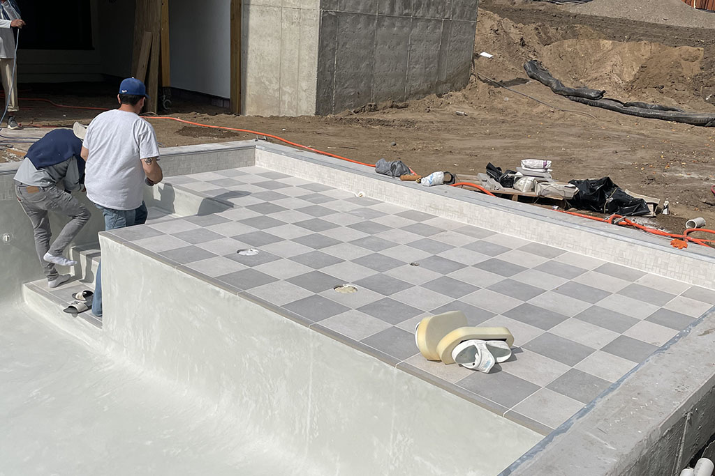 workers installing tiles in a custom pool Signature Pools