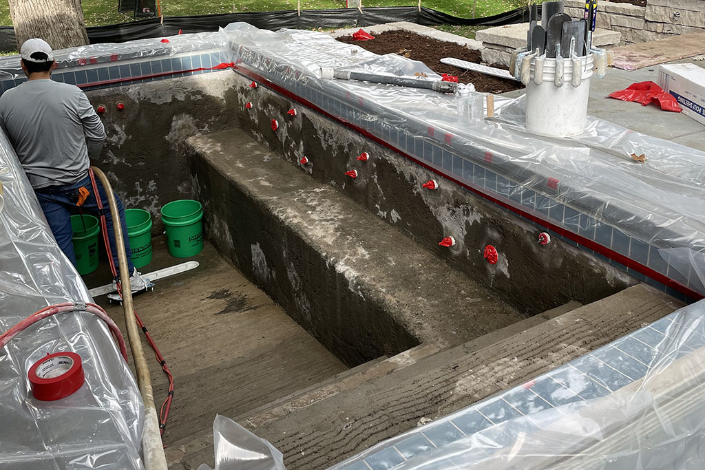 worker pouring concrete for a custom pool foundation by Signature Pools